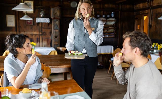 Sommelier delle mele accompagna due persone nella degustazione, annusando la mela.