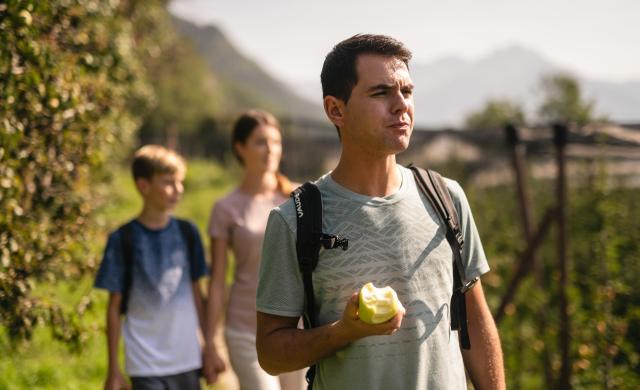 Famiglia in cammino tra i meleti dell'Alto Adige.