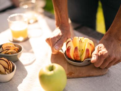 Mela appena affettata, succo di mela e chips di mela su un tavolo.